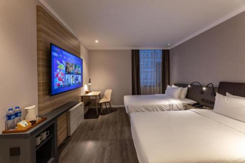 a hotel room with two beds and a flat screen tv at Hanting Premium Hotel Taizhou Wanda Plaza in Taizhou