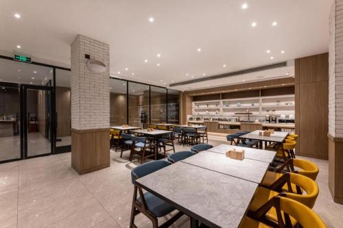a restaurant with tables and chairs in a building at Hanting Premium Hotel Taizhou Wanda Plaza in Taizhou