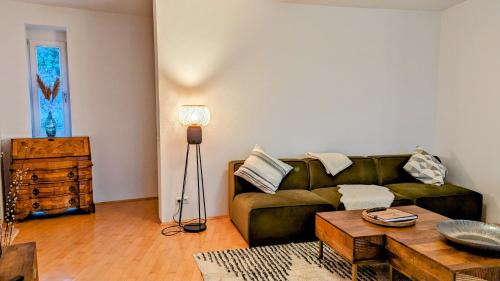 a living room with a green couch and a table at LIBORIA I Villa mit Seeblick 10min vom See in Herrsching am Ammersee