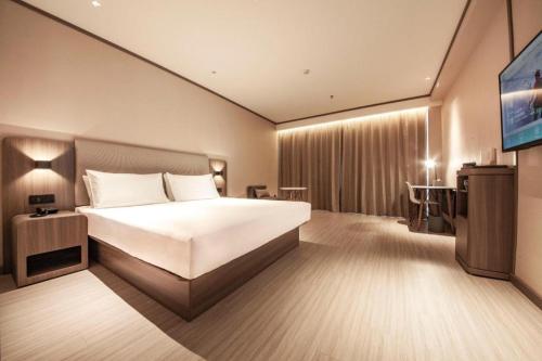 a hotel room with a bed and a television at Hanting Hotel Shenyang Jiangdong Street Metro Station in Shenyang