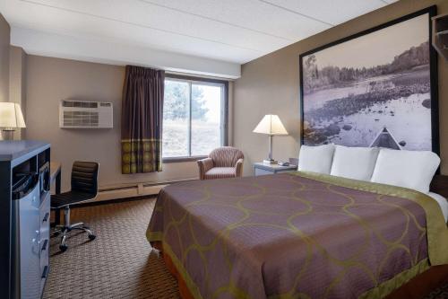 a hotel room with a bed and a large window at Super 8 by Wyndham Owatonna in Owatonna
