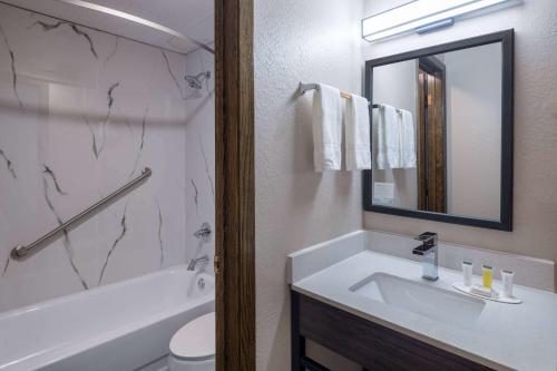 a bathroom with a sink and a tub and a mirror at Super 8 by Wyndham Owatonna in Owatonna