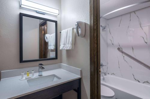 a bathroom with a sink and a toilet and a mirror at Super 8 by Wyndham Owatonna in Owatonna