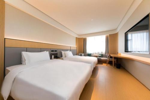 2 camas blancas en una habitación con ventana en Ji Hotel Nanjing Commercial Building en Nankín