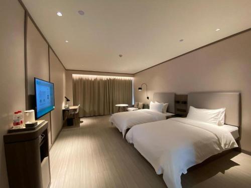 a hotel room with two beds and a flat screen tv at Hanting Hotel Jining Jinyu Road in Jining