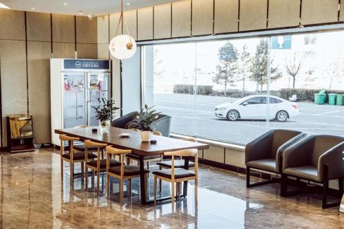 Hanting Premium Hotel Ordos Kangbashi Scenic في أوردوس: غرفة طعام مع طاولة وكراسي وسيارة بيضاء