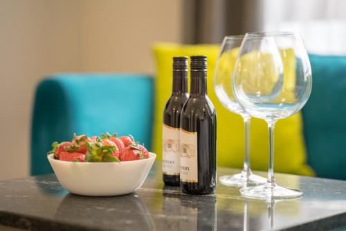 a bottle of wine and a bowl of strawberries and a wine glass at WOW studios for rent 2 bul Montevideo 25A - B in Sofia