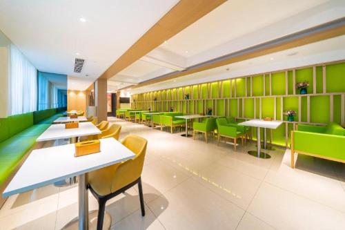 a restaurant with green walls and tables and chairs at Hanting Hotel Shanghai Jiading New Town Malu in Jiading