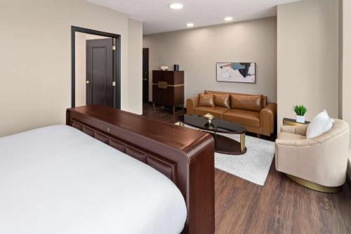 a bedroom with a bed and a living room at Legacy Hotel, Trademark Collection by Wyndham in Green Bay