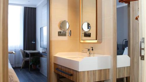 a bathroom with a white sink and a mirror at Hanting Premium Hotel Shanghai Puqingcheng Zhongxi Road in Qingpu