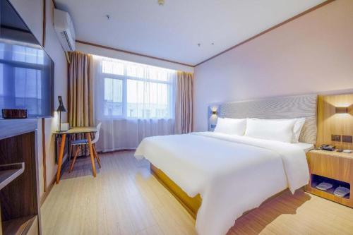 a bedroom with a large white bed and a window at Hanting Hotel Shijiazhuang Xingtang Longzhou West Street in Xingtang