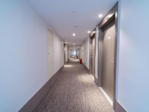 um corredor de um edifício de escritórios com um longo corredor em Hanting Hotel Wuhan Shumin Zhijia em Jiang'an