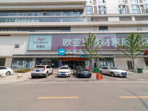 a parking lot with cars parked in front of a building at Hanting Hotel Wuhan Shumin Zhijia in Jiang'an