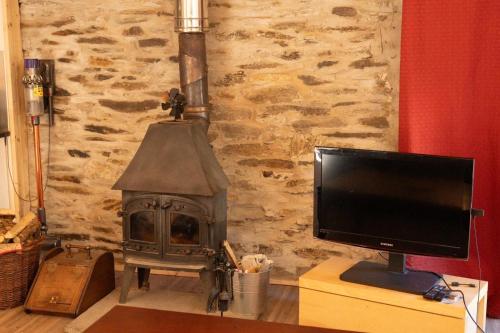 a television sitting next to a stone wall with a fireplace at Yr Ysgubor Converted milking parlour in Llandysul