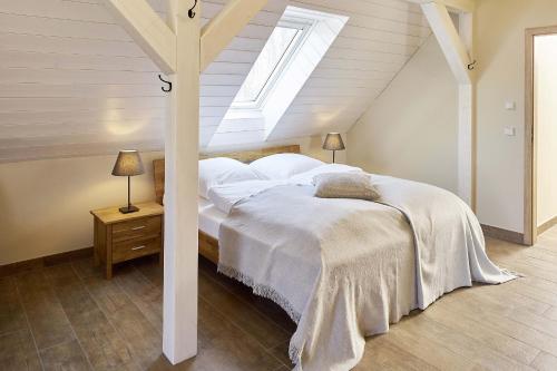 a bedroom with a bed with white sheets and a skylight at Alte Scheune in Rietz Neuendorf