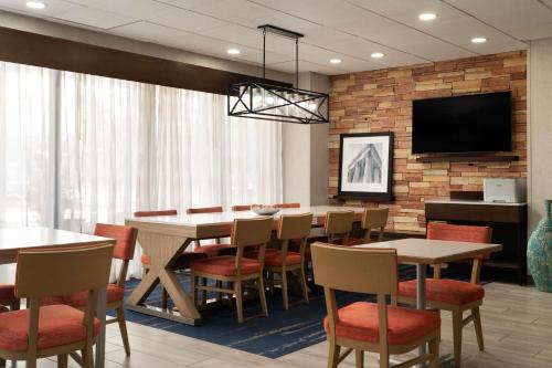 a dining room with tables and chairs and a flat screen tv at Hampton Inn Fairfax City in Fairfax