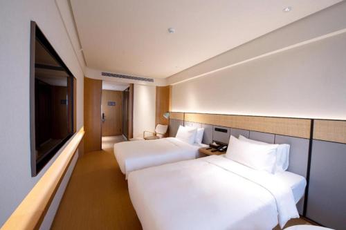 Un ou plusieurs lits dans un hébergement de l'établissement Ji Hotel Qingdao Shandong Road Mixc