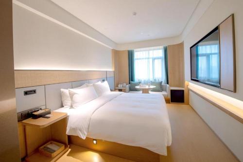 ein Schlafzimmer mit einem großen weißen Bett und einem Fenster in der Unterkunft Ji Hotel Qingdao Shandong Road Mixc in Qingdao