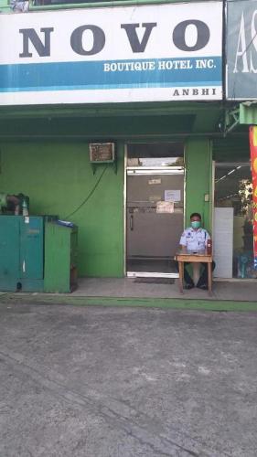 a man sitting on a table in front of a building at Asia Novo Boutique Hotel-Cabuyao in Bigaa
