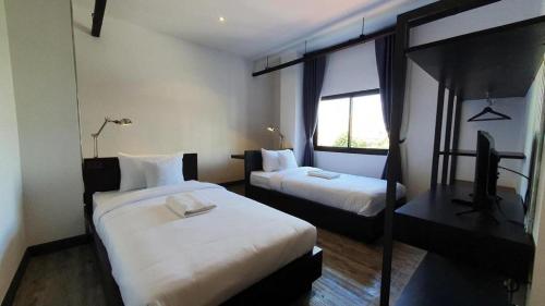 a hotel room with two beds and a window at ZK Hotel Chiangmai in Chiang Mai