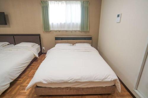 two twin beds in a room with a window at Direct to Namba,Korean town201 in Osaka