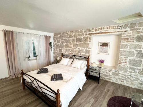 Un dormitorio con una pared de piedra y una cama en Dani Apartments, en Split