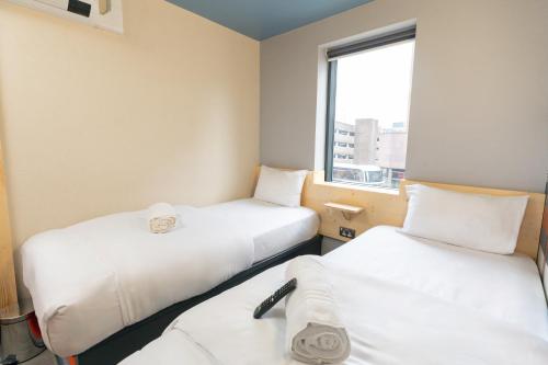 two beds in a small room with a window at easyHotel Glasgow City in Glasgow