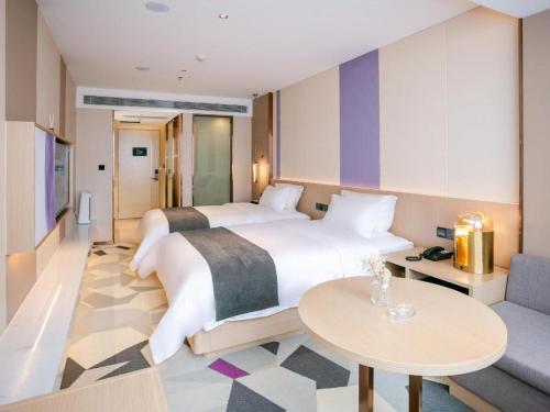 Cette chambre comprend 2 lits et une table. dans l'établissement Lavande Hotel Huizhou World Trade Center, à Huizhou