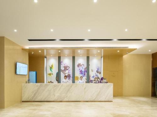 a lobby with a counter with flowers on the wall at Lavande Hotel Zhongshan Xiaolan Taifeng in Jilong