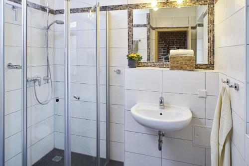 a white bathroom with a sink and a shower at Sanddornhaus in Rietz Neuendorf