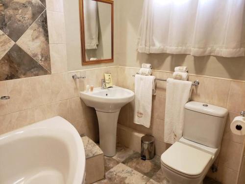 a bathroom with a white toilet and a sink at Selborne Hotel in Bulawayo