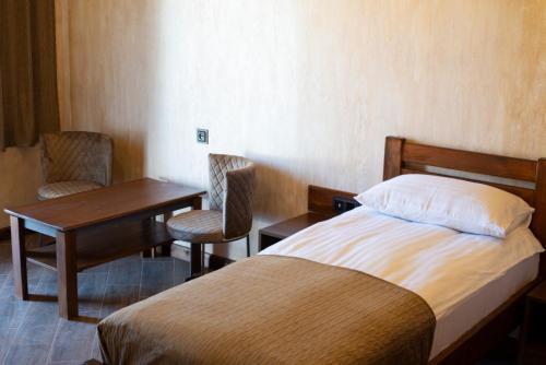 a bedroom with a bed and a table and chairs at Amroc Hotel - Հյուրանոց Ամրոց in Noyemberyan