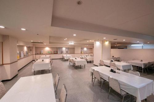 een eetkamer met witte tafels en witte stoelen bij Main Hotel in Miyakonojo