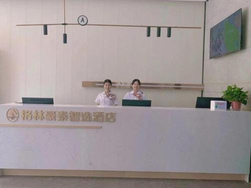 Dos mujeres sentadas en un mostrador en una oficina en Green Tree Inn Express Chizhou Gymnasium, en Pai-sha-p'u