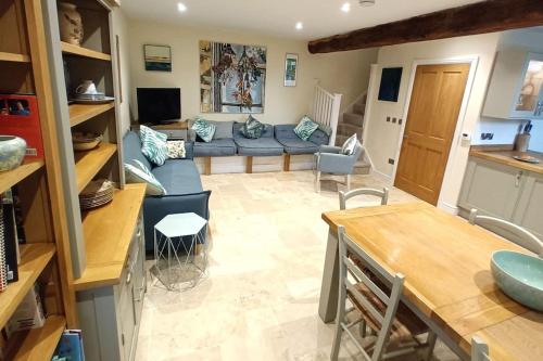 sala de estar con sofá azul y cocina en Luxury Country Bolthole Near Soho Farmhouse, en Middle Barton