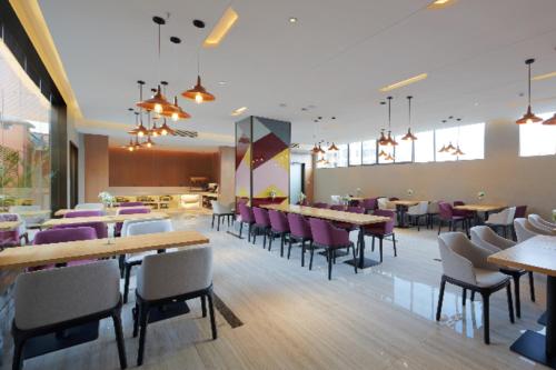 ein Restaurant mit Tischen, Stühlen und lila Stühlen in der Unterkunft Borrman Hotel Liuzhou Liujing District Government in Liuzhou