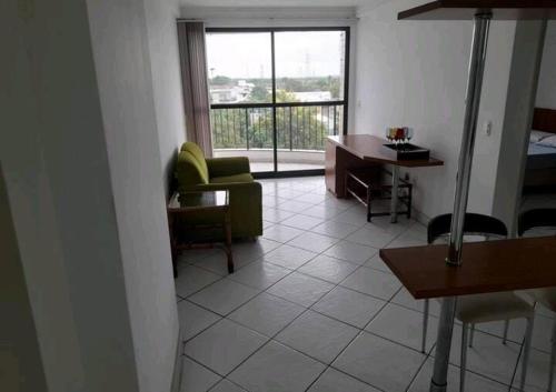 a living room with a couch and a desk and a window at Flat centro - Via Park in Campos dos Goytacazes