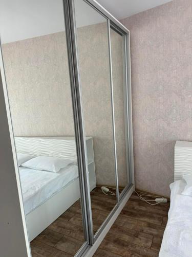 a bedroom with a mirror next to a bed at Апартамент Градски Парк in Dobrich