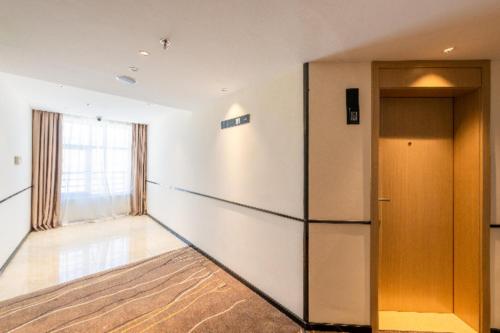 een lege kamer met een koelkast en een raam bij City Comfort Inn Shannan Passenger Terminal in Nedong