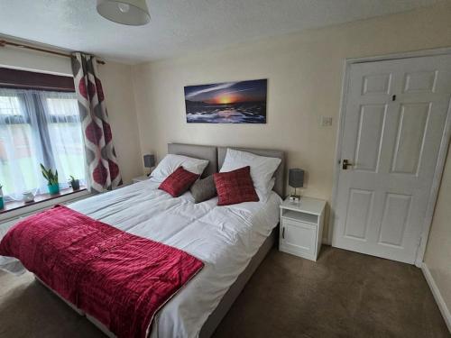 1 dormitorio con 1 cama blanca grande con almohadas rojas en Hidden Gem, en Eastbourne