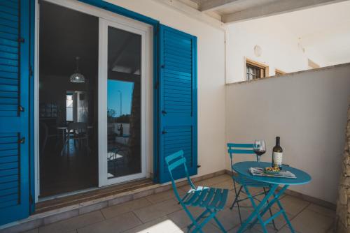 a patio with blue chairs and a table with a glass of wine at Tabarano Holiday Apartment by Diddoi in Torre Suda