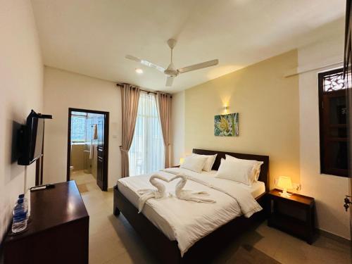 a bedroom with a large bed and a television at Moi Hikka by DBI in Hikkaduwa