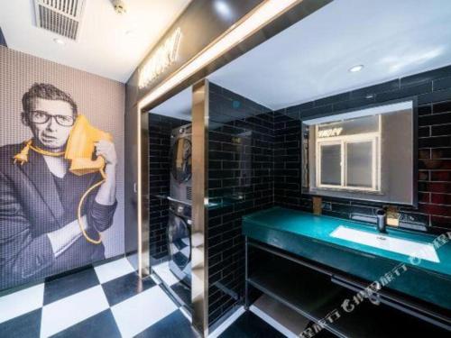 un baño con una pintura de un hombre con teléfono en Premier City Comfort Hotel Suizhou Wuyue Plaza, en Suizhou