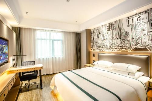 a bedroom with a bed and a desk and a television at City Comfort Inn Yidu Three Gorges Qianguqing Wanda Plaza in Yidu