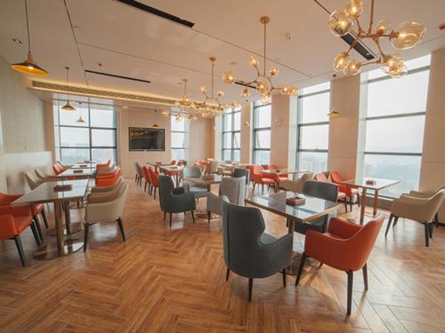 a restaurant with tables and chairs and windows at Echarm Hotel Shiyan Beijing South Road Hanjiang Normal College in Shiyan