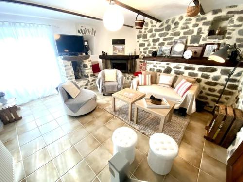 - un salon avec un canapé, des chaises et un mur en pierre dans l'établissement La ferme de mon grand-pėre, Gîte les Bourriaux 6p 3ch, à Saint-Pons
