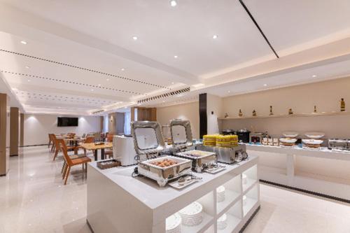 a restaurant with a buffet line with tables and chairs at City Comfort Inn Yancheng Xihuan Road Wanda Plaza in Yancheng