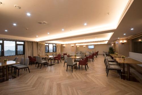 a dining room with tables and chairs and windows at Echeng Hotel Enshi Minzu Road in Enshi