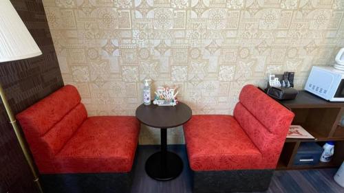 two red chairs and a table in a room at Anekkusu Nishihara intā mae in Minamiuebaru