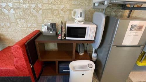 a kitchen with a microwave on a table next to a refrigerator at Anekkusu Nishihara intā mae in Minamiuebaru
